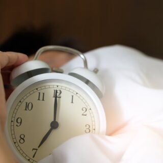 hand holding clock in bed
